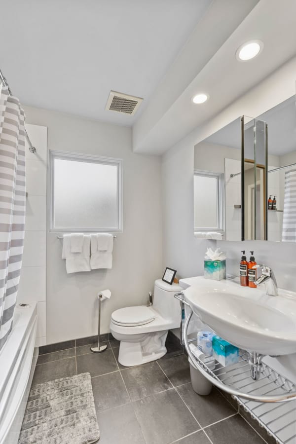 Interior view of a modern bathroom with a bathtub, sink, and gray tiled floor.
