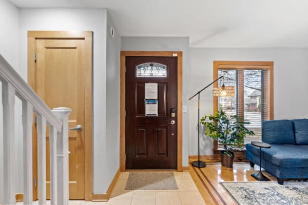 Entrance area featuring a dark wooden door, blue couch, and natural light from a window.