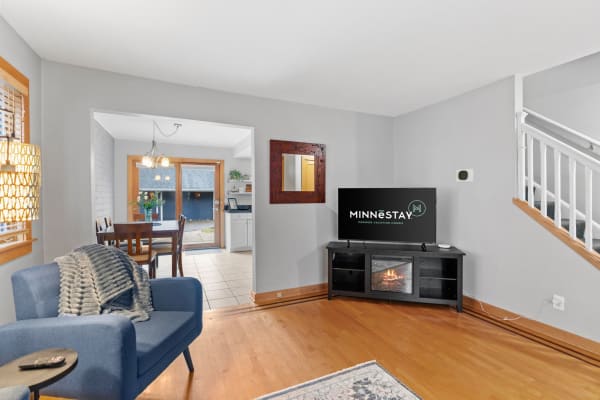 Cozy living room with modern furniture, TV, and dining area in view.