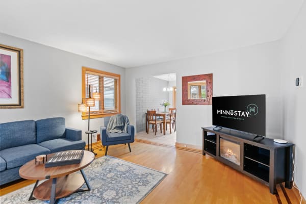 Living room with a blue sofa, television, and dining area visible.