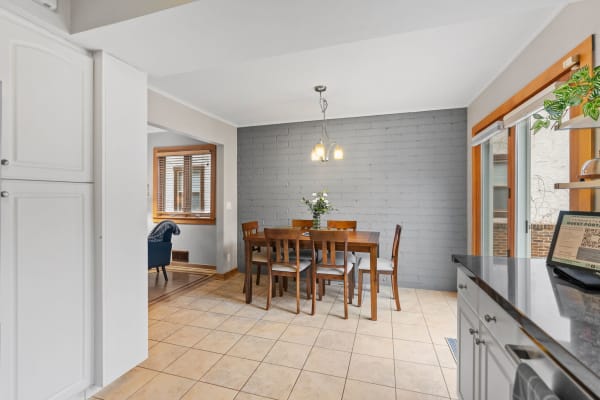 Modern dining area with a wooden table, grey brick wall, and natural light from a window.