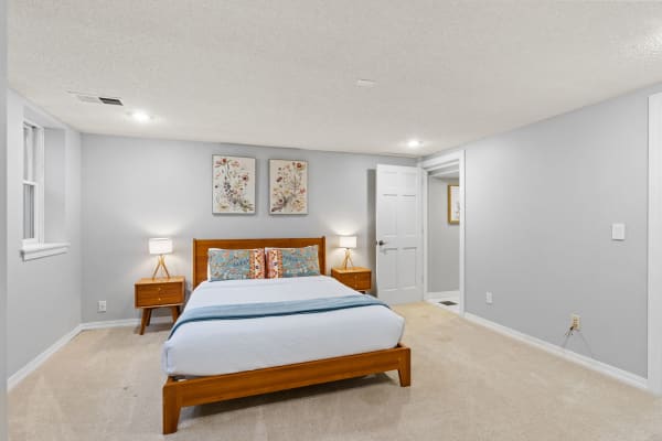 Cozy bedroom with wooden furniture, decorative pillows, and floral art.