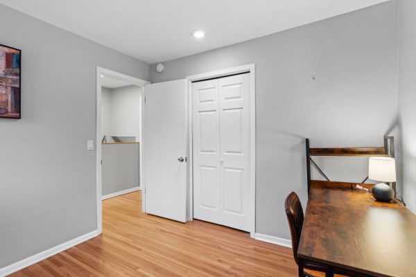 A minimalist room with a wooden desk, gray walls, and hardwood flooring.