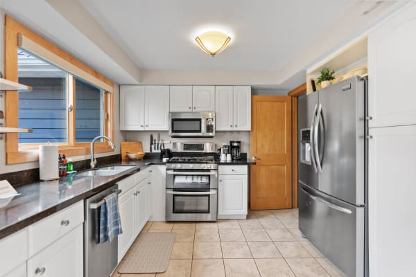 Bright and modern kitchen with white cabinets and a stainless steel refrigerator.