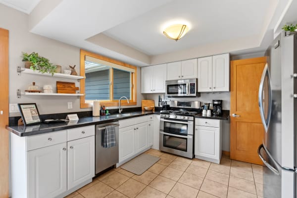 Spacious kitchen featuring white cabinets, black granite countertops, and stainless steel appliances.