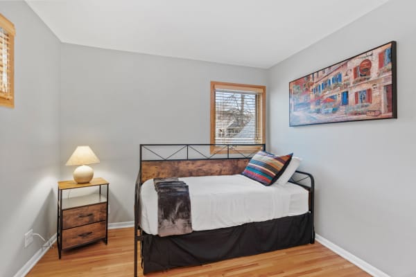 A well-decorated bedroom with a daybed, nightstand, and colorful wall art.