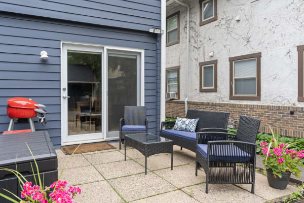 Outdoor patio with a grill, wicker chairs, and a flower pot.