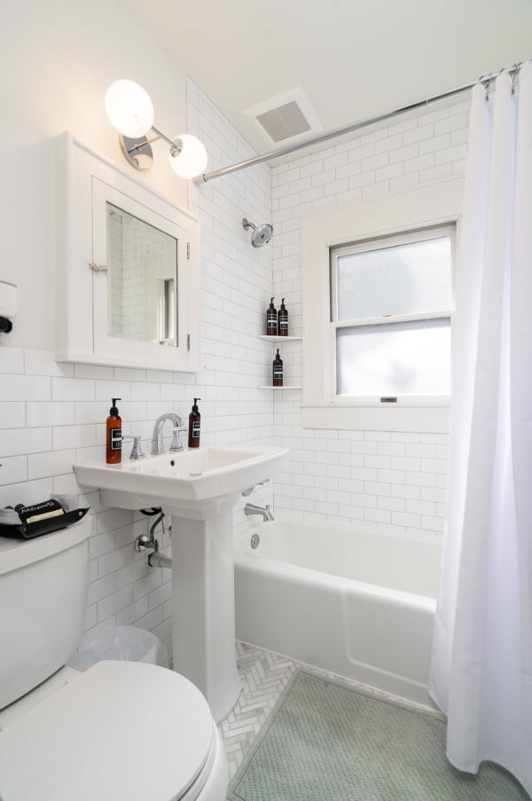 A bright and clean bathroom with white subway tiles, a bathtub, and modern fixtures.