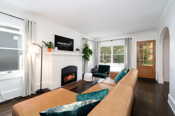 Modern living room with a leather sectional, green armchair, and fireplace.