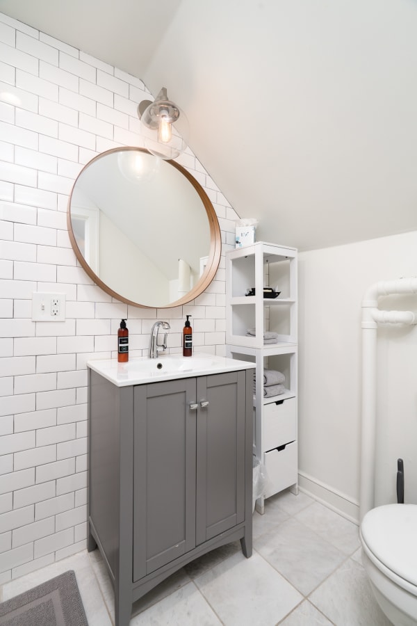Contemporary bathroom with gray vanity and white subway tiles.