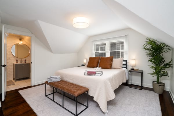 A modern bedroom featuring a queen-sized bed, stylish nightstand, and a doorway leading to a bathroom.