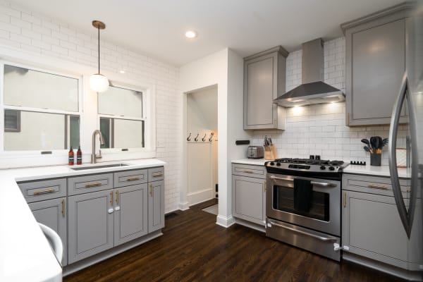 Contemporary kitchen featuring gray cabinetry, stainless steel appliances, and white subway tiles.