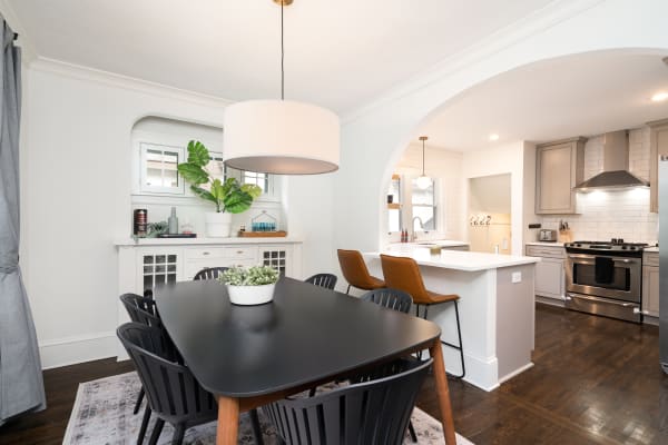 Contemporary dining area with black table, chairs, and connecting kitchen.