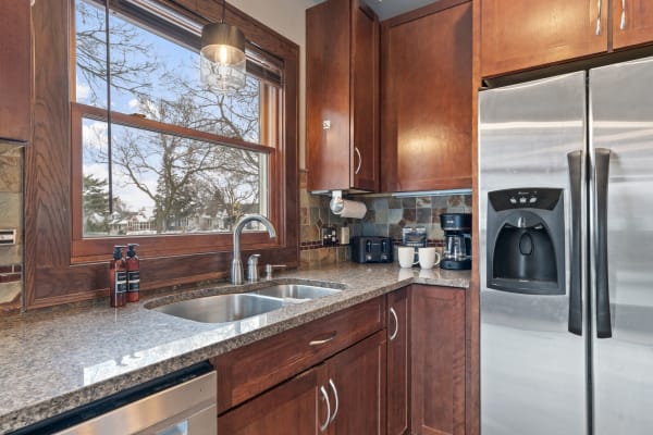 Modern kitchen with wooden cabinets, granite countertop, and large window.