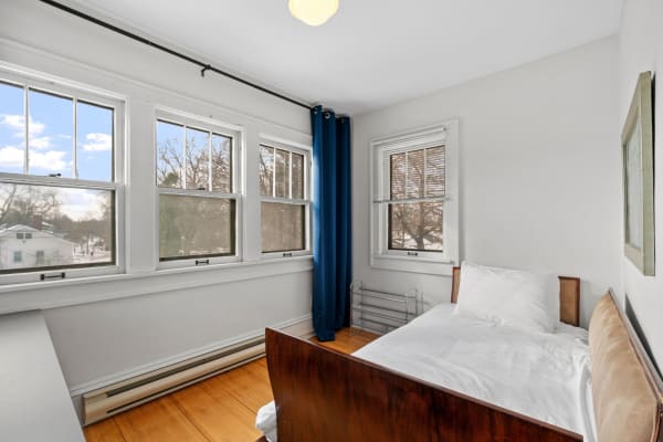 Cozy bedroom interior with a bed, large windows, and blue curtains.