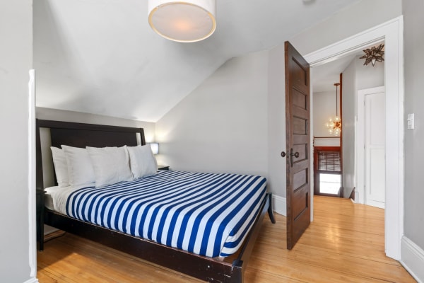 Attic bedroom with a striped bed and wooden flooring.