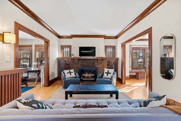 Cozy living room featuring blue chairs, a dark wooden coffee table, and a brick fireplace.