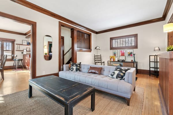 A cozy living room with a light gray sofa, dark wooden coffee table, and vibrant artwork.