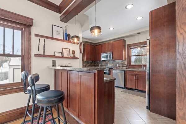 Cozy kitchen featuring wood cabinets, stainless steel appliances, and decorative shelves.