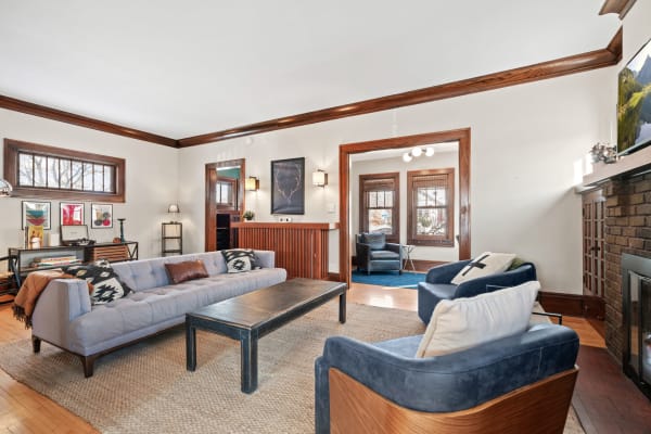 Stylish living room featuring a light blue sofa, dark coffee table, and deep blue armchairs, with warm wood accents.