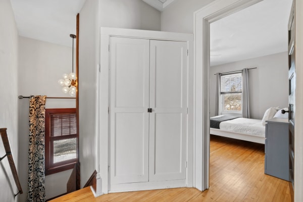 Interior view of a staircase landing with a modern light fixture and doorway to a bedroom.