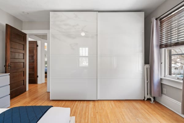 Interior of a modern bedroom with a white wardrobe and hardwood flooring.