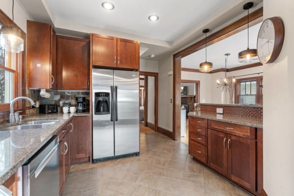 Modern kitchen featuring wooden cabinets, stainless steel refrigerator, and granite countertops.