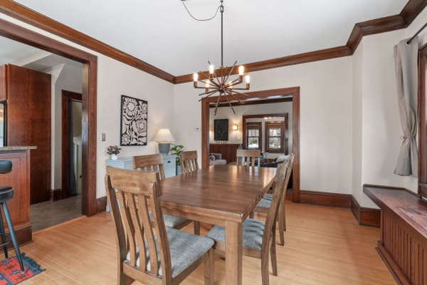Dining room with wooden table, chairs, chandelier, and decorative elements.