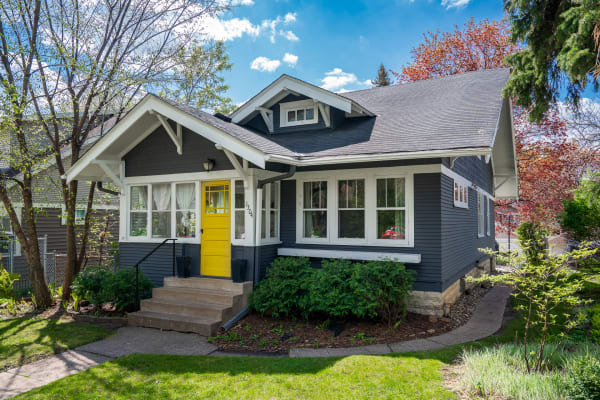 A picturesque house with a yellow front door and surrounded by greenery.