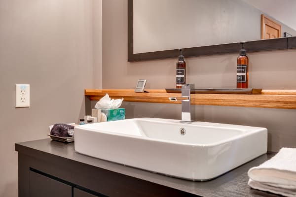 Contemporary bathroom sink with a stylish faucet, soap dispenser, and toiletries.