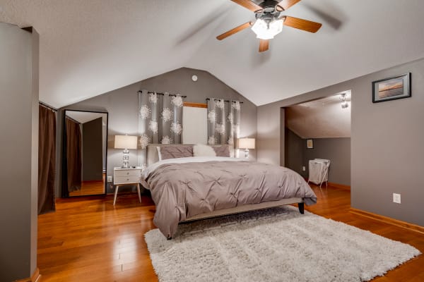 A stylish bedroom featuring a queen-sized bed, bedside lamps, and a plush rug on wooden flooring.