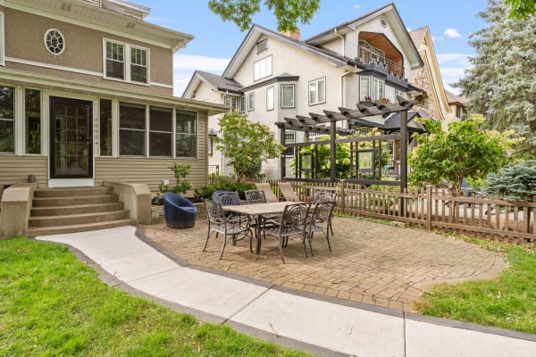 A patio with a dining table and chairs in a green backyard surrounded by houses.