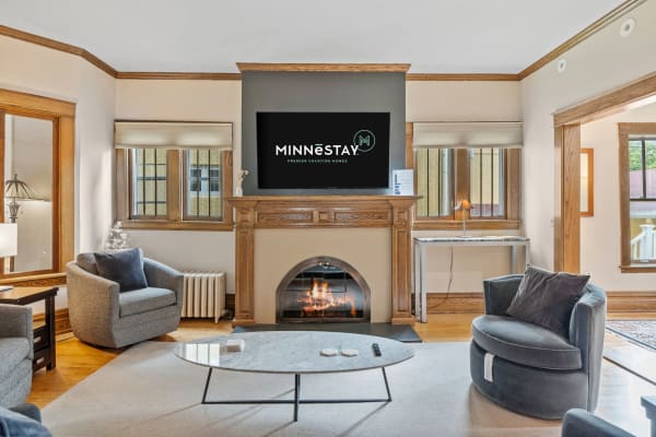 A stylish living room with a fireplace, TV above it, and comfortable seating.