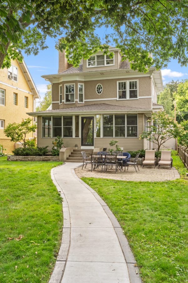 Three-story house with a front yard and seating area.