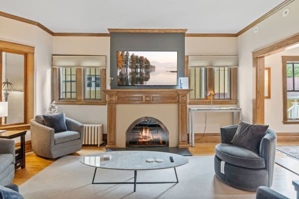 Cozy living room featuring a fireplace, circular coffee table, and flat-screen TV with a landscape image.