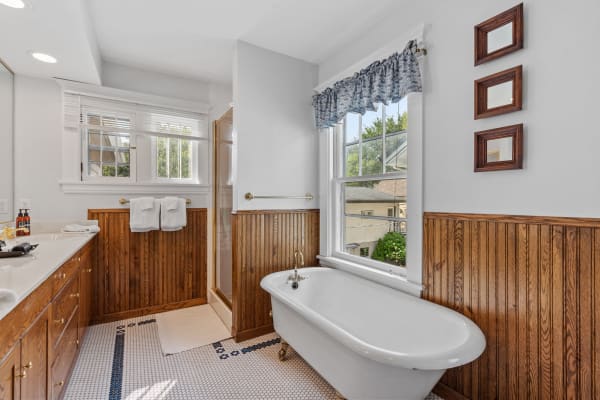 Spacious bathroom with freestanding bathtub, wooden paneling, and a large window.