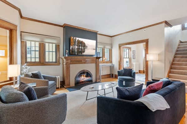 Cozy living room with black sectional sofa, gray armchairs, and a fireplace