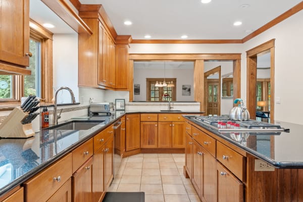 Modern kitchen with wooden cabinets, granite countertops, and stainless steel kettle.
