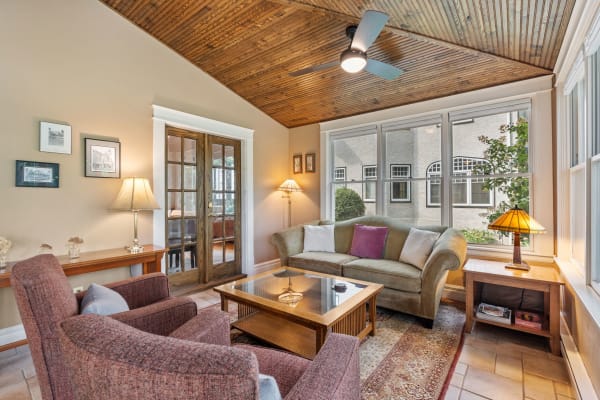Cozy living room with olive-green sofa and burgundy armchairs under a wooden ceiling.