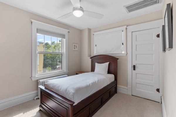 Cozy bedroom with single wooden bed, window, and white door.