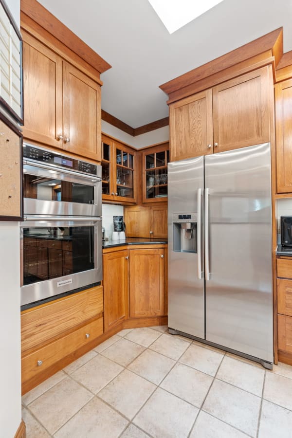 A kitchen with oak cabinets, stainless steel refrigerator, and a skylight.
