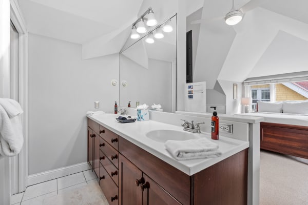 Bright bathroom with white countertop and dark wood cabinets, featuring a mirror and light fixtures.