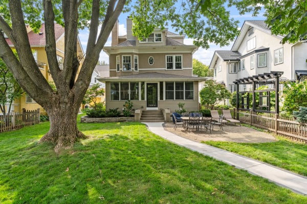 Charming multi-story house with a lush green lawn and patio.