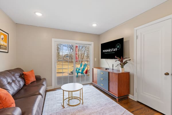 Cozy living room featuring a leather sofa, coffee table, and sliding glass doors to a deck.