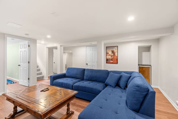 Basement living area with a blue sectional sofa and wooden coffee table.