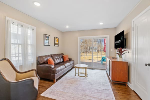 Bright living room with leather sofa, decor, and sliding glass doors opening to the patio.