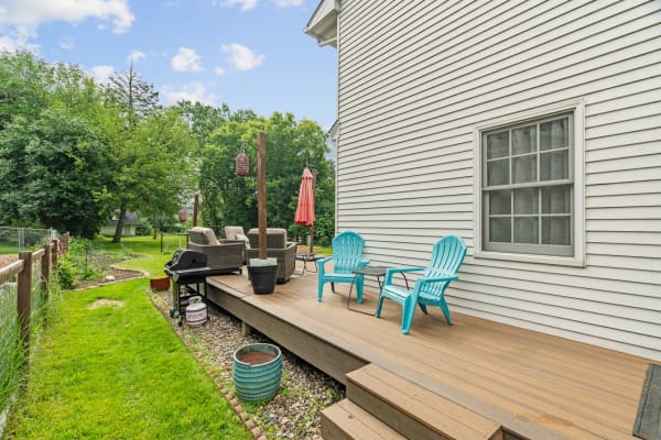 A wooden deck with turquoise chairs and outdoor seating, surrounded by greenery.
