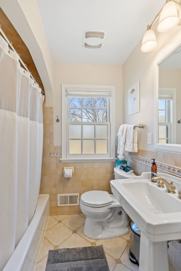Cozy bathroom featuring a white sink, beige tiles, and a frosted window.