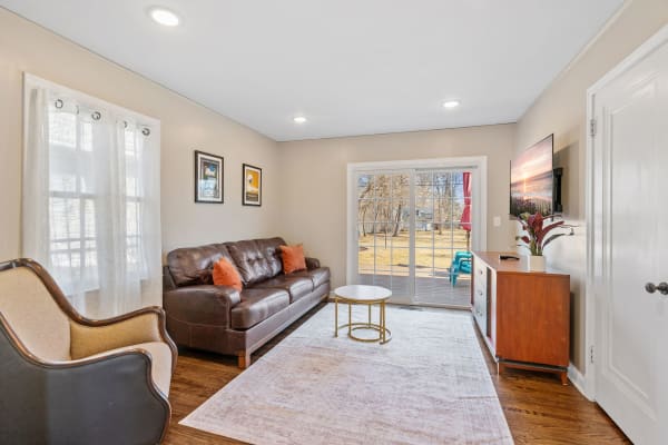 Comfortable living room featuring a leather sofa, coffee table, and outdoor views through sliding glass doors.
