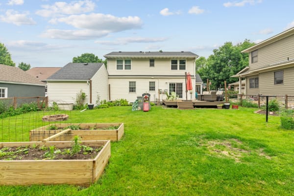 Spacious backyard featuring raised garden beds and a patio with outdoor seating.